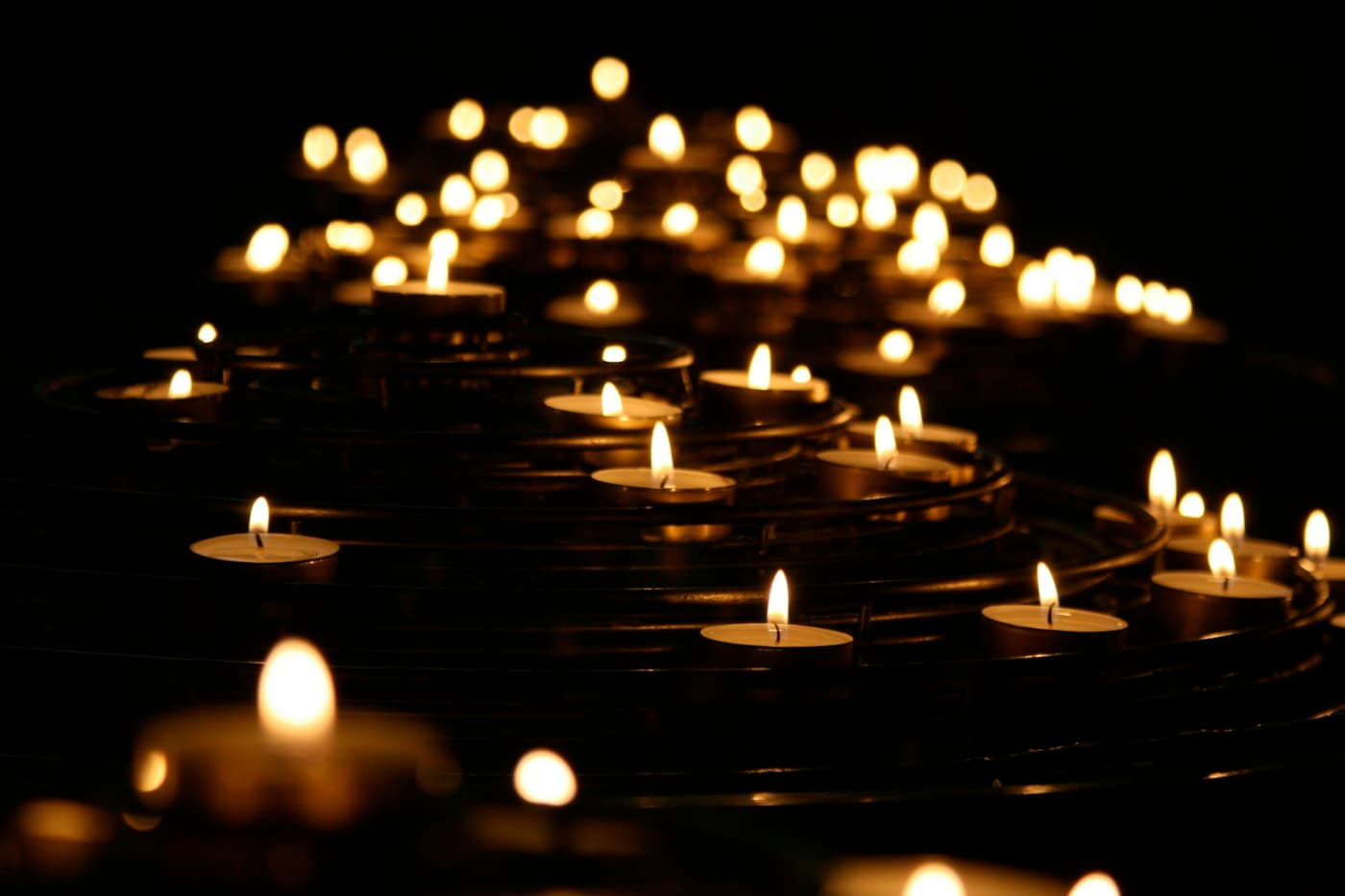 Rows of lit votive candles glowing in a dark church