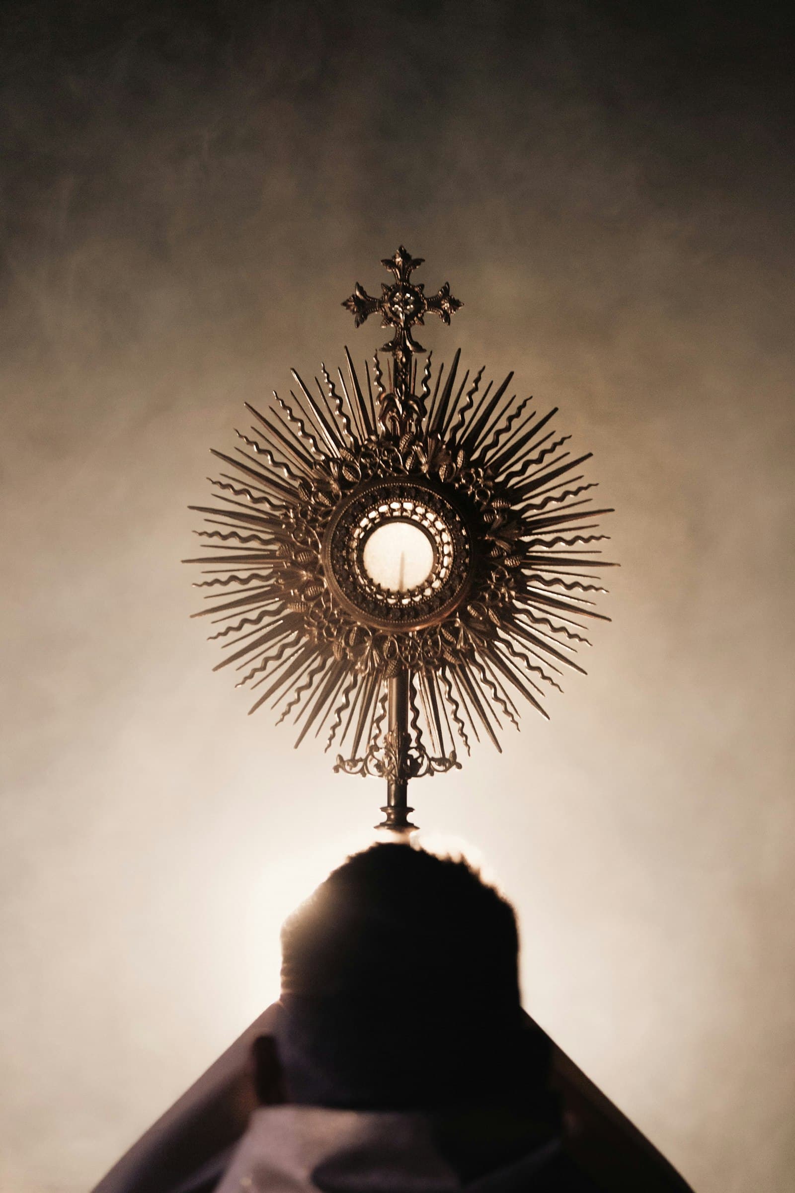 A golden monstrance raised against soft light